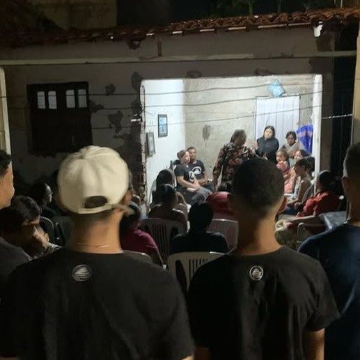 Reunião de oração à noite em um quintal, com jovens reunidos