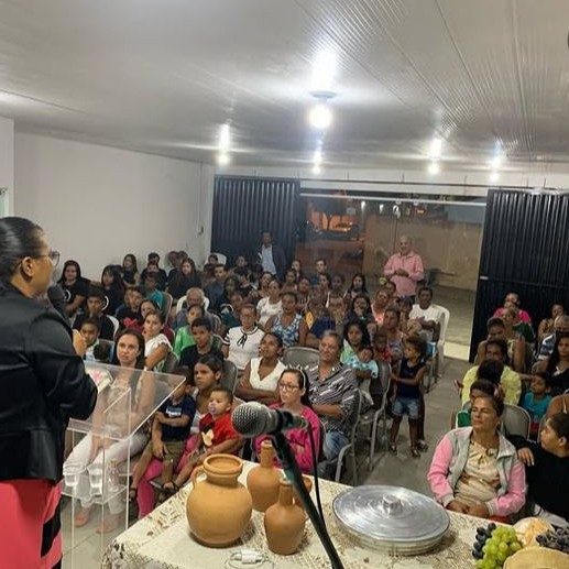 Risa Elin pregando diante de uma congregação sentada