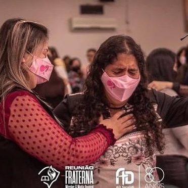 Congregação de mulheres com as mãos erguidas em oração